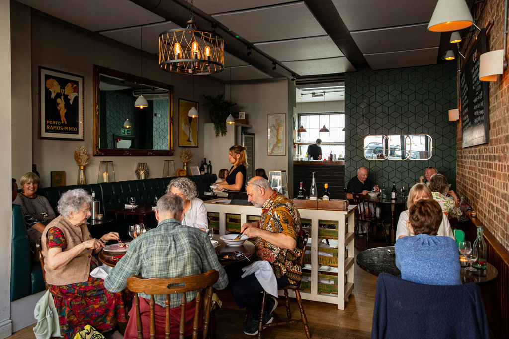 A busy restaurant of people dining during the day time.