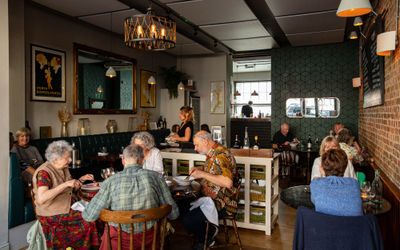 A busy restaurant of people dining during the day time.