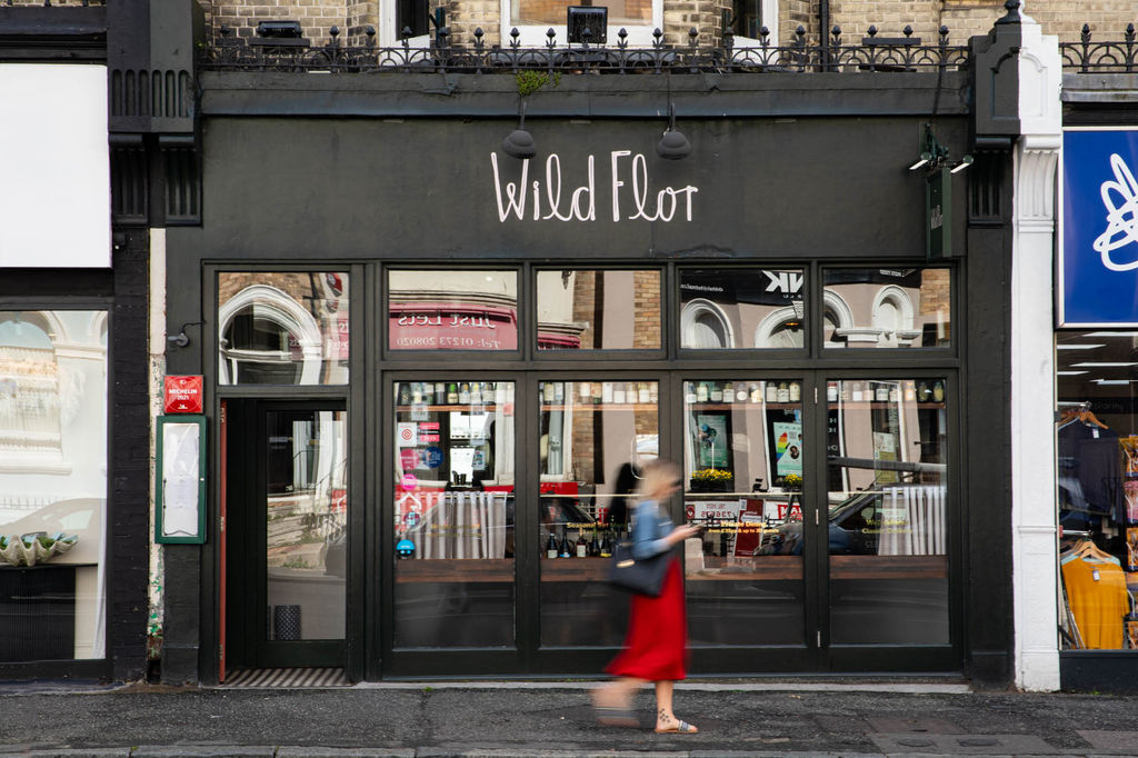 The exterior of Wild Flor restaurant in Hove with a lady walking past in a red dress.