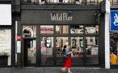 The exterior of Wild Flor restaurant in Hove with a lady walking past in a red dress.