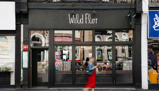 The exterior of Wild Flor restaurant in Hove with a lady walking past in a red dress.