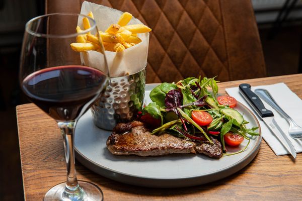 steak and veggies on the plate served with chips and glass of red wine