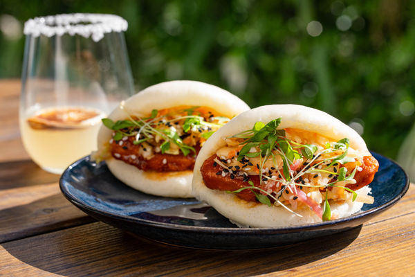 Bao buns on a plate with a cocktail.