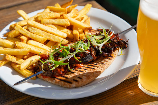 Golden fries served alongside a grilled flatbread topped with veggies on stick