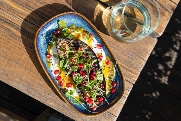 Overhead shot of a colourful aubergine dish on a sunny table.