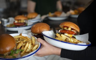 Burgers and fries in brioche buns served on enamel dishes