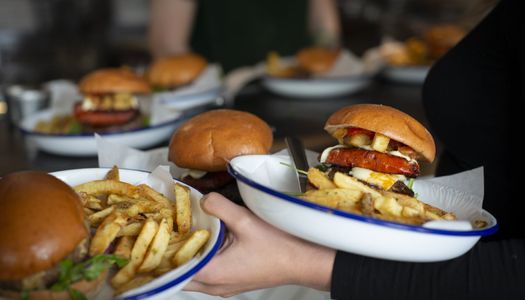 Burgers and fries in brioche buns served on enamel dishes