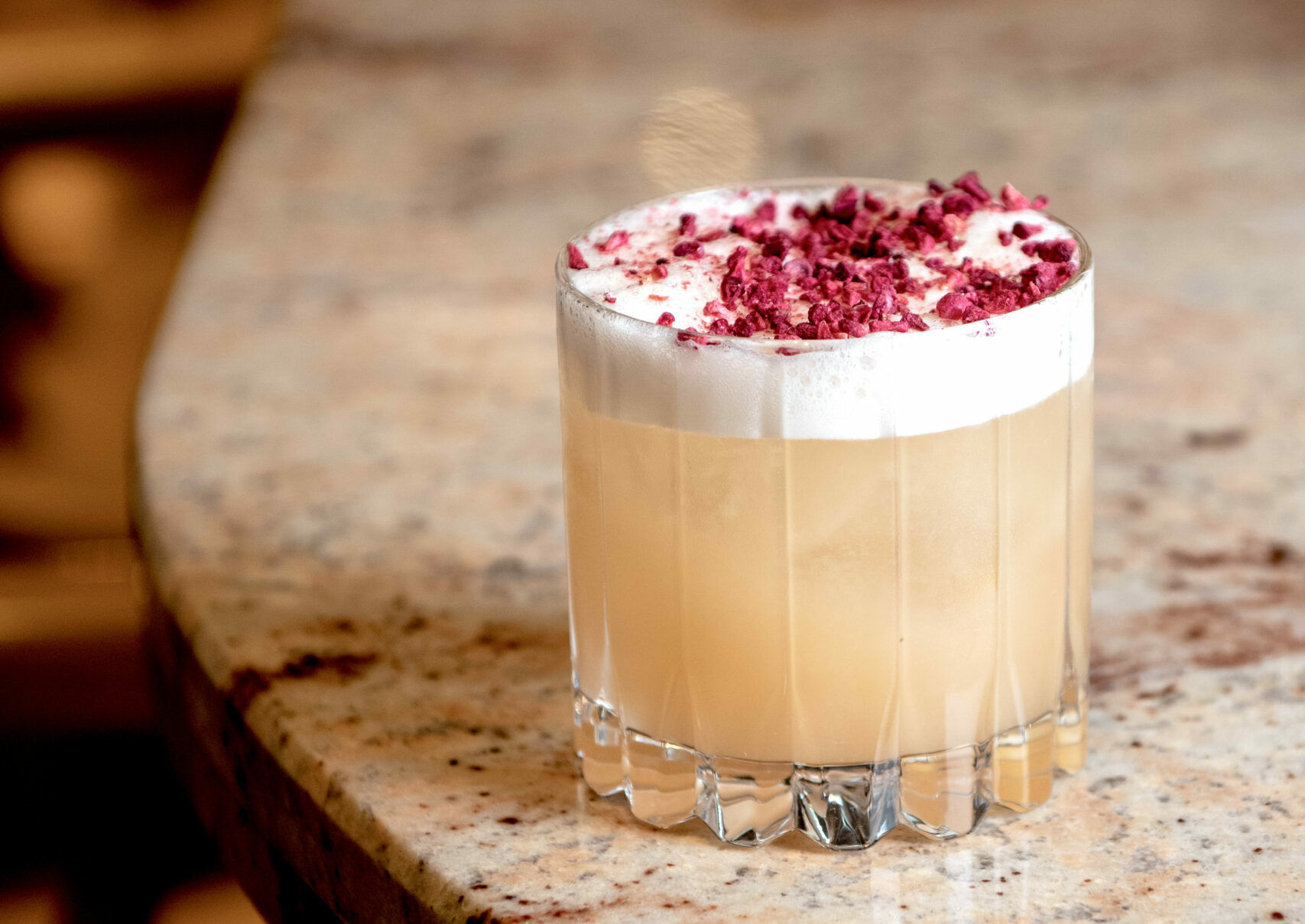 peach coloured cocktail with the foam and red decoration on the top. Kindling restaurant