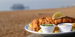 Fish & chips served with a wedge of lemon along with small pots of tartare sauce and mushy peas. The Brighton Seafront restaurant Guide.