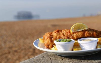 Fish & chips served with a wedge of lemon along with small pots of tartare sauce and mushy peas. The Brighton Seafront restaurant Guide.