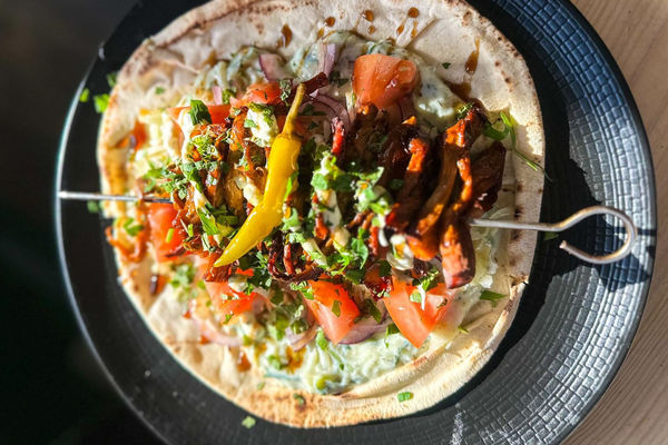 An overhead photo of a flatbread loaded with fresh, vibrant colourful vegan ingredients.