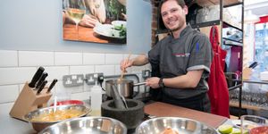 one of the chefs smiling at the camera whilie mixing ingredients inside pot