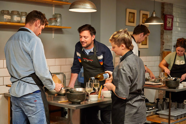 few people chatting over cooking table at Brighton Cookery School