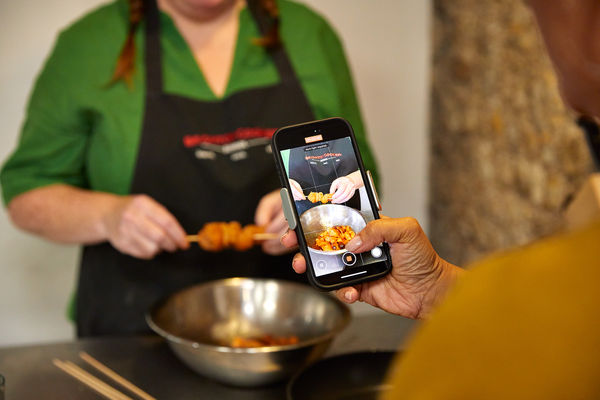 person taking photo of another person who is cooking during cooking class at Brighton Cookery School