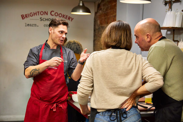 Chef Victor talking to the couple during cooking class at Brighton Cookery School
