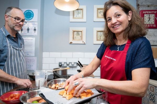woman smiling at the camera while adding some carrots into bowl