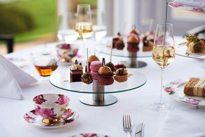 French patisserie desserts and sweets served on glass cake stands with china teacups and champagne.