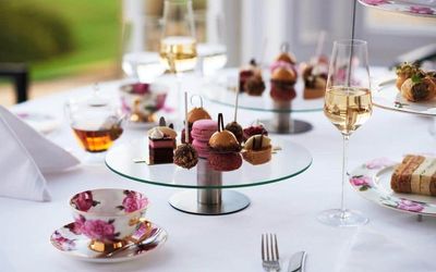 French patisserie desserts and sweets served on glass cake stands with china teacups and champagne. Afternoon tea and cake