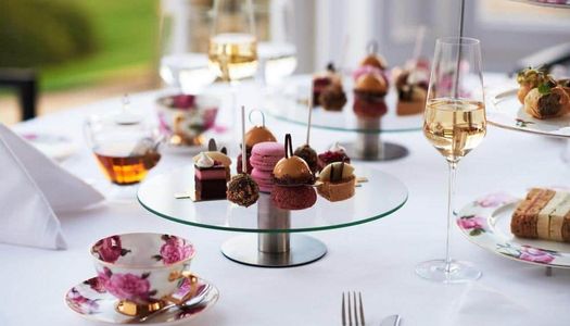 French patisserie desserts and sweets served on glass cake stands with china teacups and champagne.