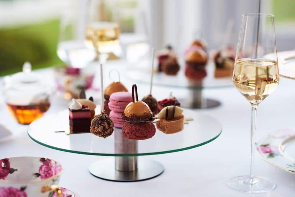 Pretty French patisserie sweets served on a glass cakes stand with glasses of champagne.