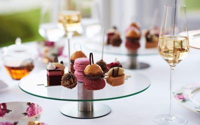 Pretty French patisserie sweets served on a glass cakes stand with glasses of champagne.
