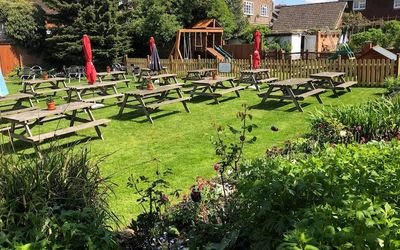 Traditional kitchen garden with a children’s play area. Wooden benches lined up with parasols and plant pots.