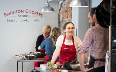 shot of the woman smiling and looking at the man during brighton cookery school cooking class