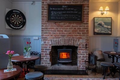 Rustic interior with seating and a wood burner against a brick wall.