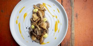 Wild mushroom dish served on a grey plate with a yellow sauce.