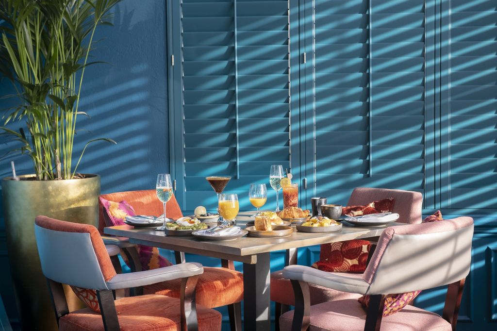 A table laid for Brunch at Cyan, with four orange chairs and beautiful light streaming through the blinds