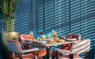 A table laid for Brunch at Cyan, with four orange chairs and beautiful light streaming through the blinds