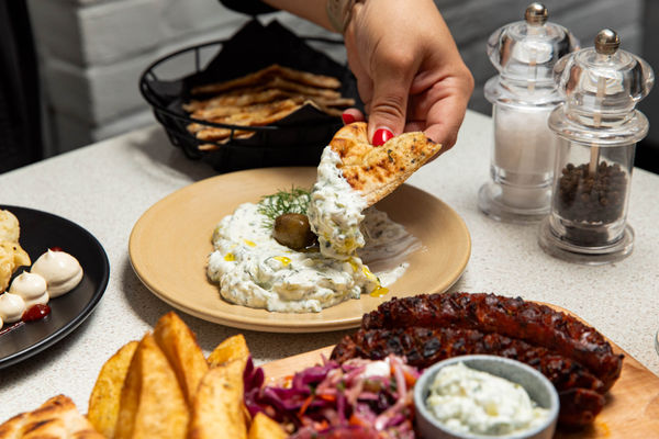 dipping Greek bread into white sauce at nostos Hove