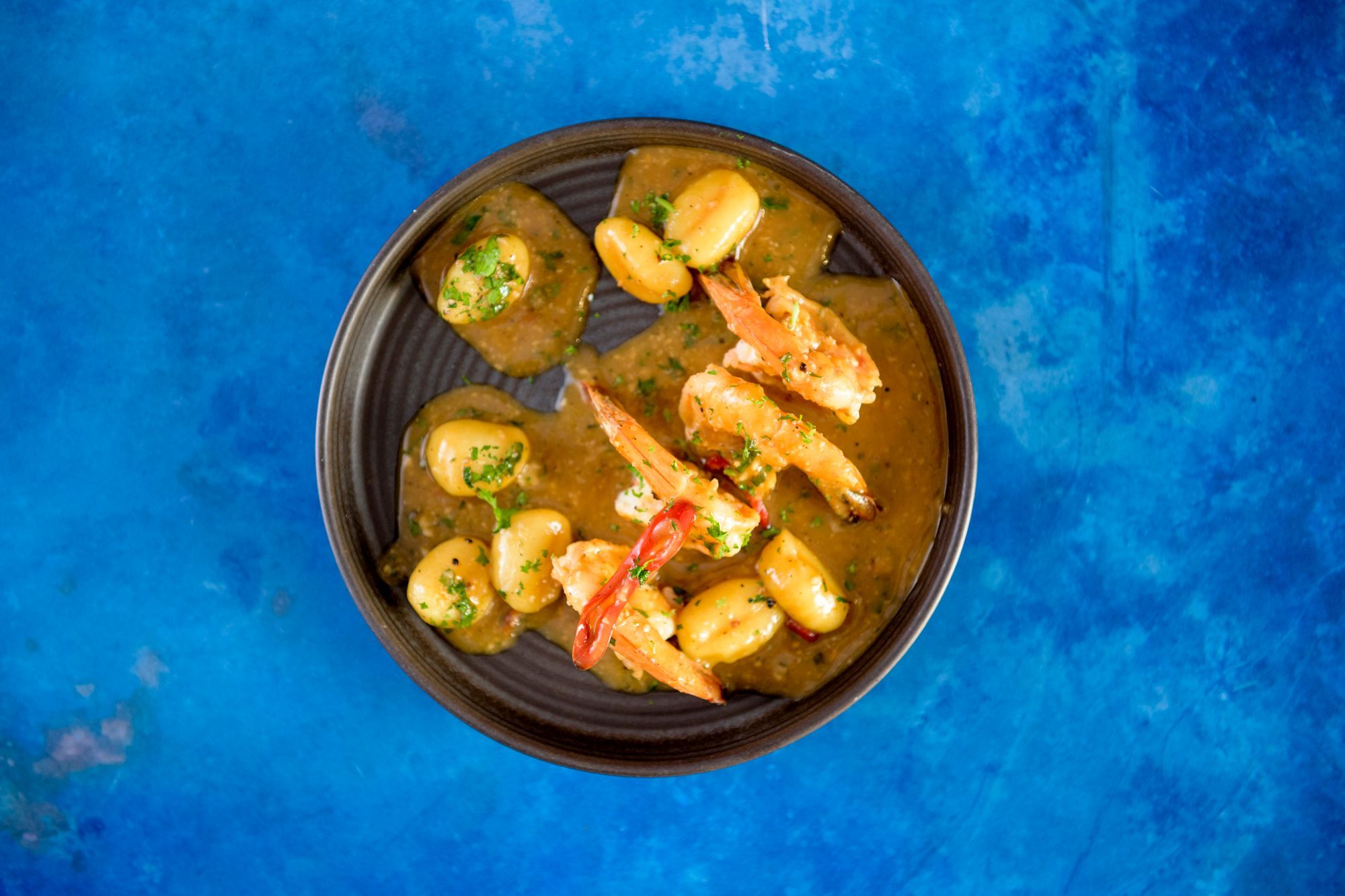 Gardies Saganaki dish - king prawns cooked in bisque, served on blue plate and blue table