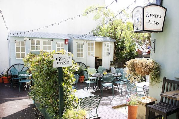 The garden at The George Payne Hove with plants, seating and a vintage caravan. Brighton Beer Garden