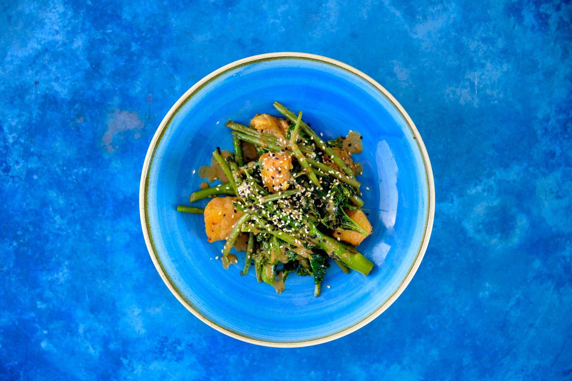 over head shot of the blue plate with green food, served on the blue table