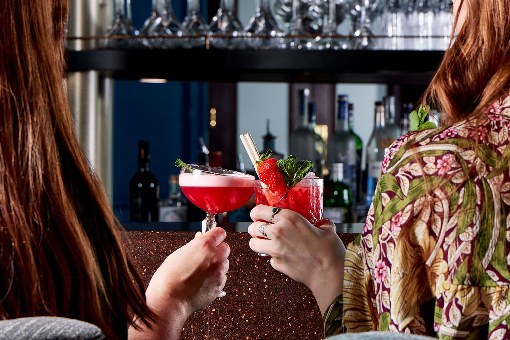 two girls having a toast with their red cocktails in the nice cocktail glasses at Cyan Brighton