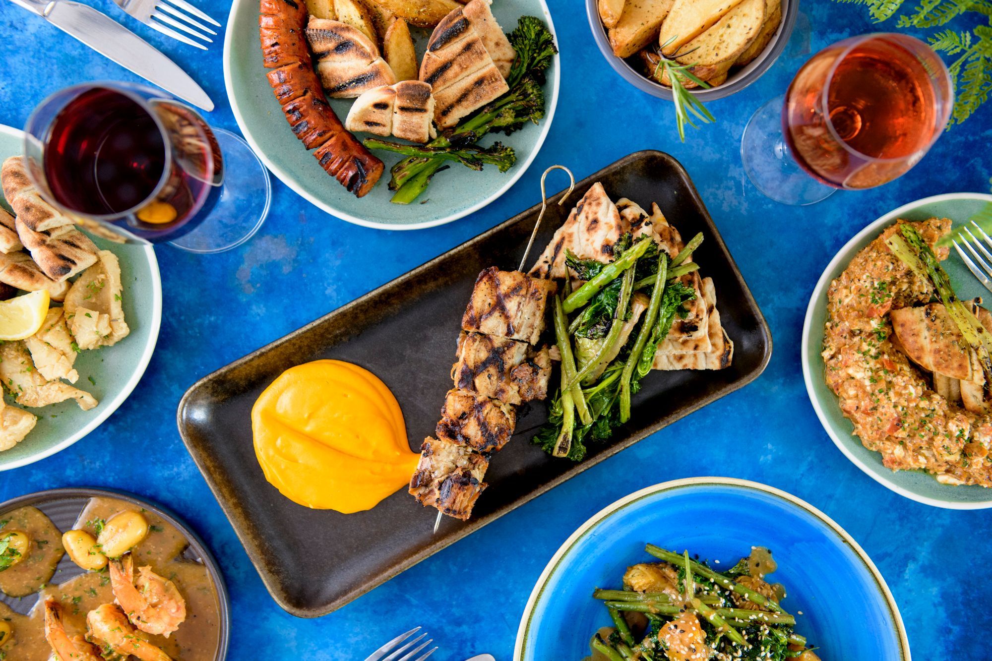 over head shot of the delicious greek dishes served in colorful plates on dark blue table