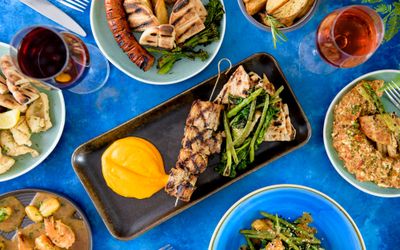 over head shot of the delicious greek dishes served in colorful plates on dark blue table