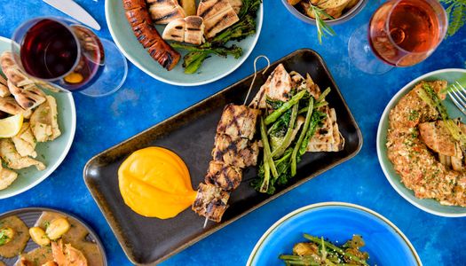 over head shot of the delicious greek dishes served in colorful plates on dark blue table