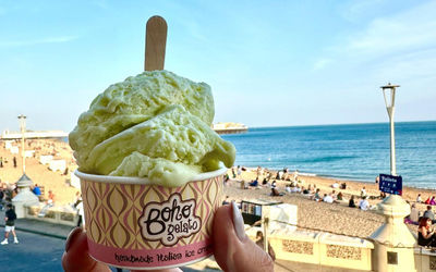 Boho Gelato at Shelter Hall A pot of ice cream being held up with the view of Brighton beach in the background.