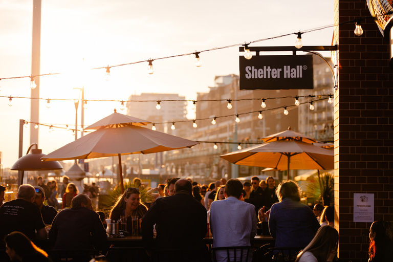 Shelter Hall Brighton, shot of people enjoying their drinks and food outside during the sunset. Shelter Hall features as part of the Restaurants in Brighton guide