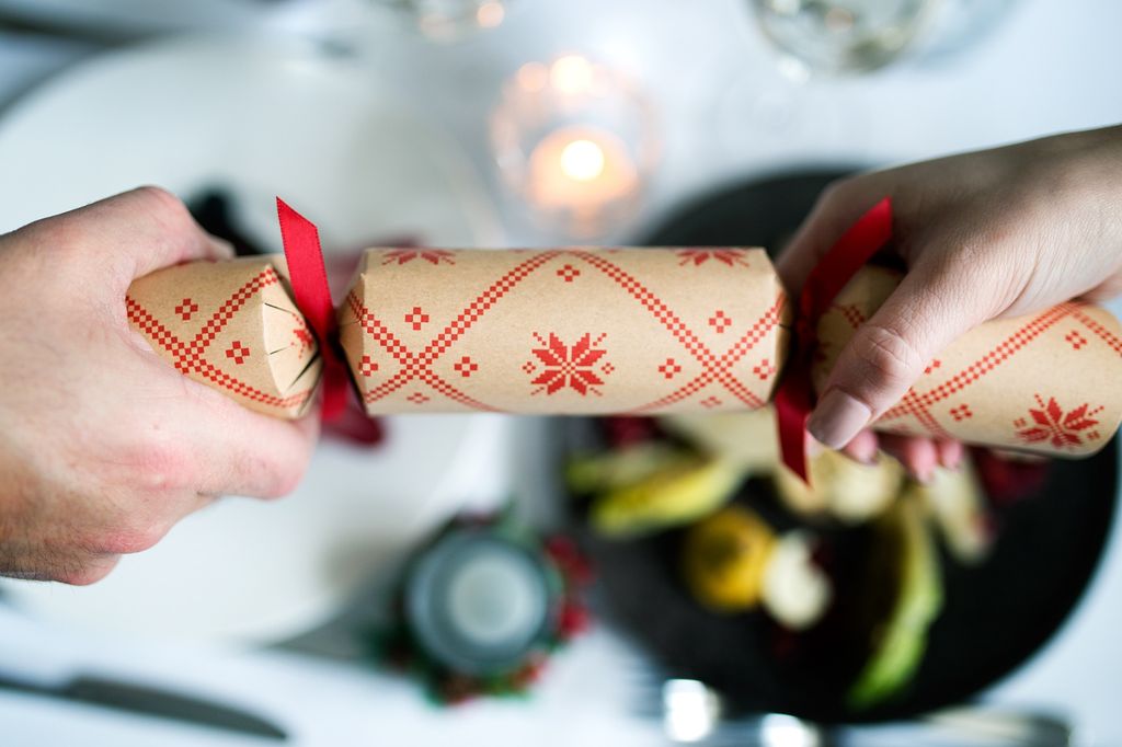 Christmas Crackers, Christmas Parties in Brighton . Christmas Party Brighton. a picture of two guests pulling a red and beige Christmas cracker over the backdrop of a white linen table cloth at one of the Brighton restaurants in our guide..