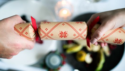 Christmas Crackers, Christmas Dinner at Drakes of Brighton. Christmas Party Brighton. a picture of two guests pulling a red and beige Christmas cracker over the backdrop of a white linen table cloth at one of the Brighton restaurants in our guide..