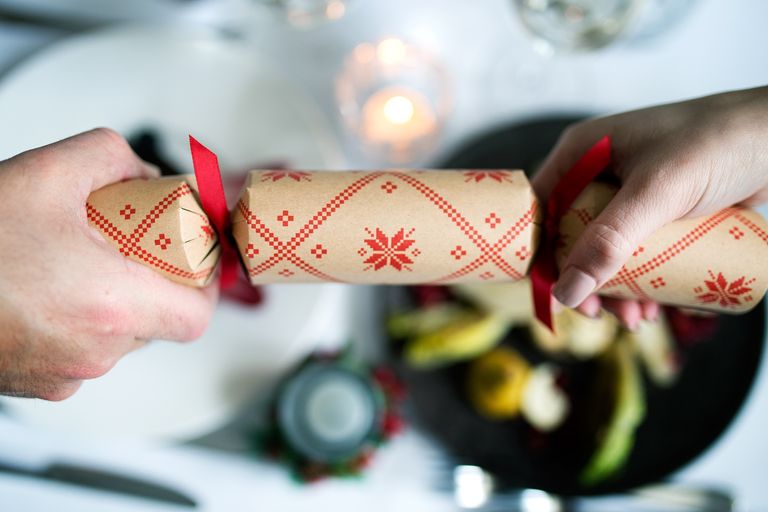 Christmas Crackers, Christmas Parties in Brighton . Christmas Party Brighton. a picture of two guests pulling a red and beige Christmas cracker over the backdrop of a white linen table cloth at one of the Brighton restaurants in our guide..