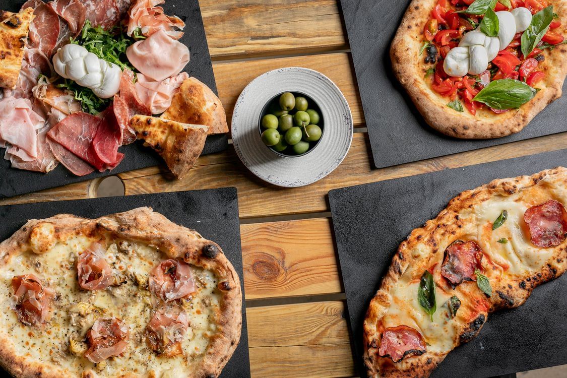 over head shot of the table at VIP pizza laid out with Italian pizzas and sandwiches