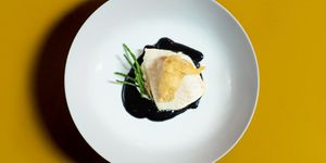 Brill with squid ink velouté , oyster tempura and samphire. Photographed on a mustard yellow table.