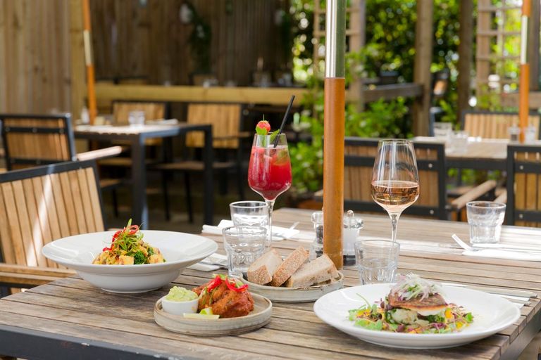 table in the garden laid out with couple of plates with dishes and drinks next to it