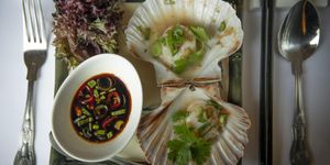 Scallops served in their shells with a dipping sauce and vintage cutlery