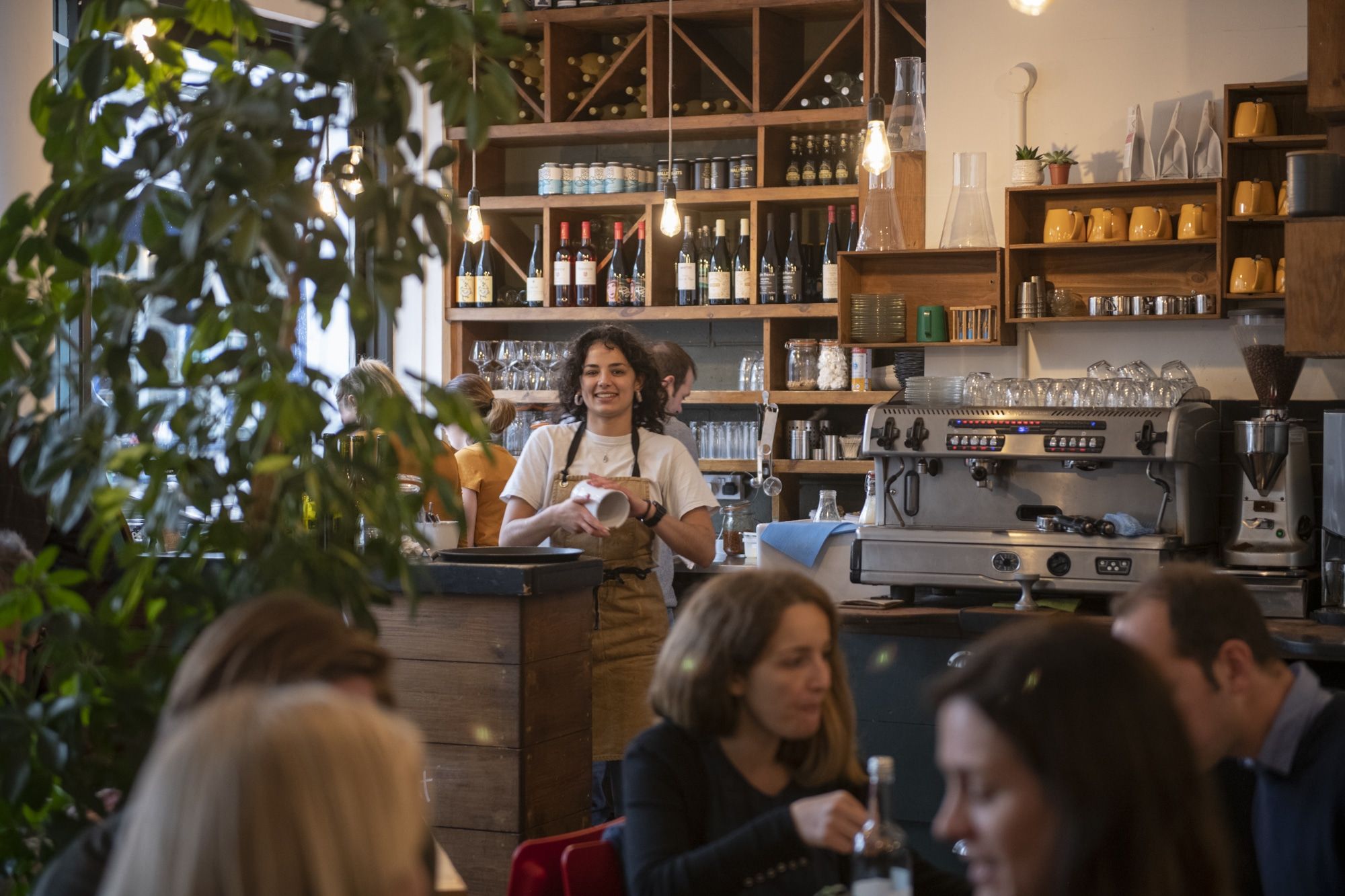 This is the Brighton Coffee Shop called Mange Tout located in Brighton's North Laine. Picture of waitress behind coffee counter, among the seating area in venue.