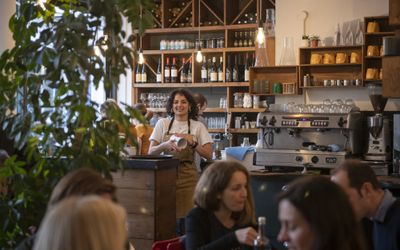 This is the Brighton Coffee Shop called Mange Tout located in Brighton's North Laine. Picture of waitress behind coffee counter, among the seating area in venue.